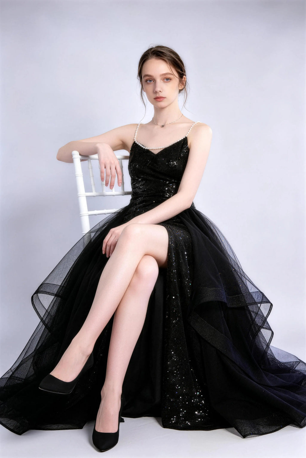 Model wearing black sequin pearl strap tulle slit evening gown