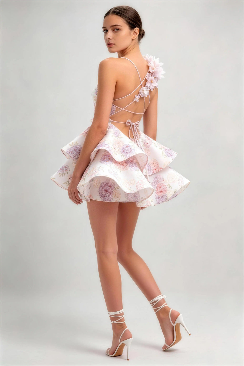 Model wearing pink 3d floral applique lace‑up back ruffled floral print mini dress