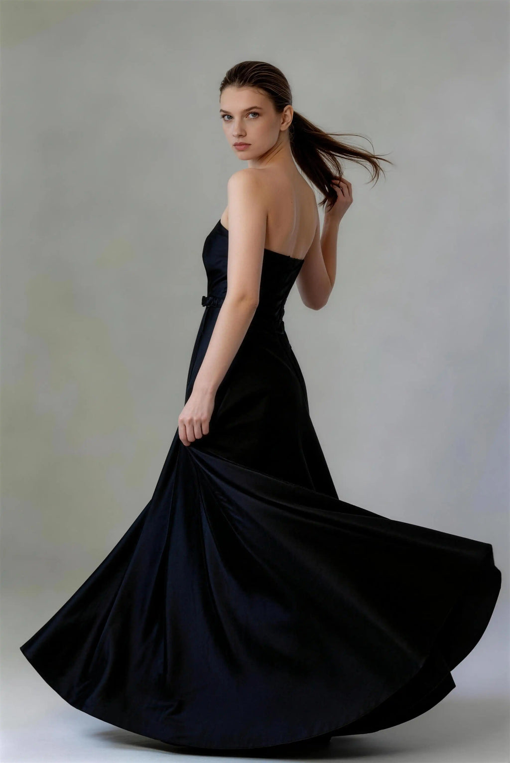 Phoehua Side Twirl View of Black Minimalist Elegant Evening Gown, Strapless Bow‑Belt Lace‑Up‑Back Mid‑Rise Satin A‑Line Formal Wedding Guest Dress