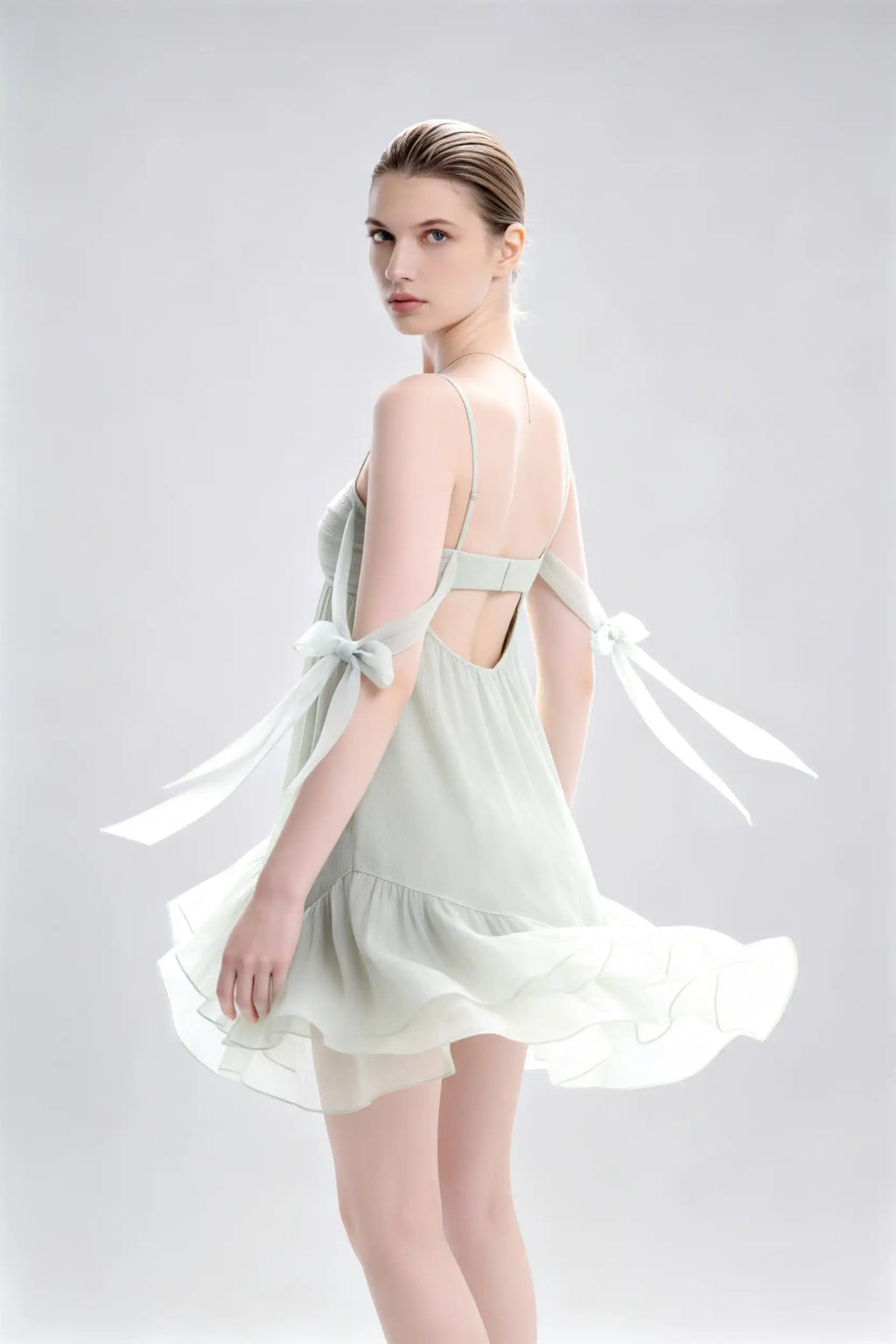 Phoehua Side Twirl View of Sage Green Romantic Summer Dress, Spaghetti‑Strap Bow‑Tie‑Strap Backless Crinkled‑Chiffon Ruffle‑Hem Party Mini Dress
