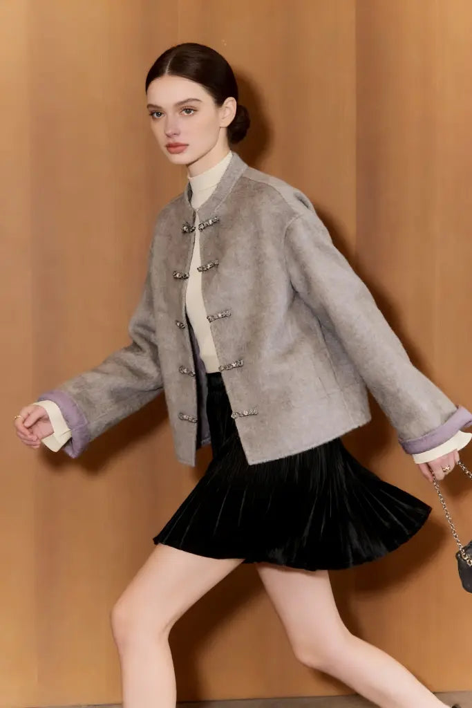 Woman wearing a gray jacket and black skirt against a beige background