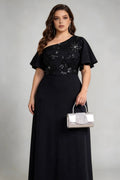 Plus size woman wearing black one-shoulder sequin evening gown with silver clutch bag, full-length view