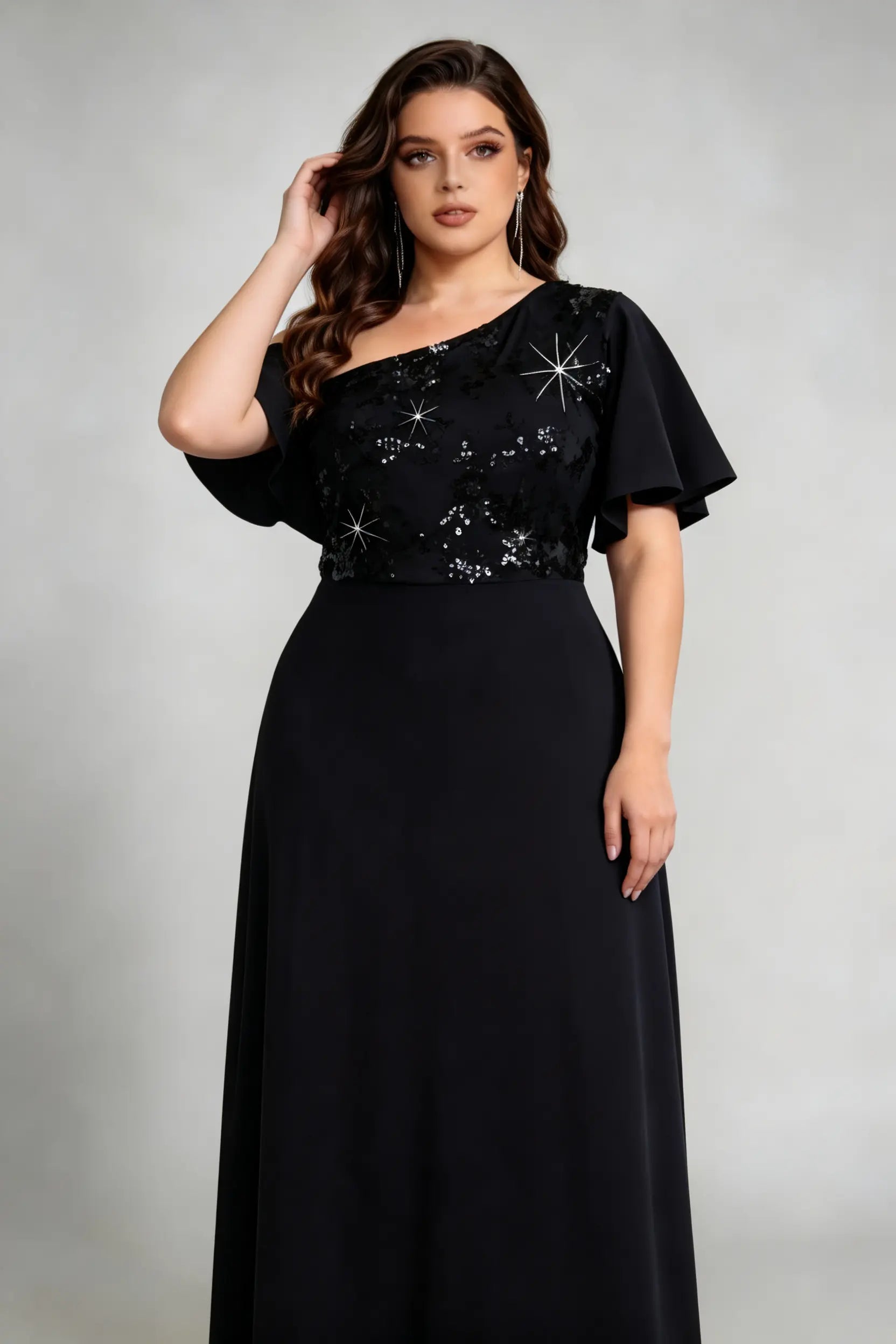 Plus size woman posing in black sequin gown with hand touching hair