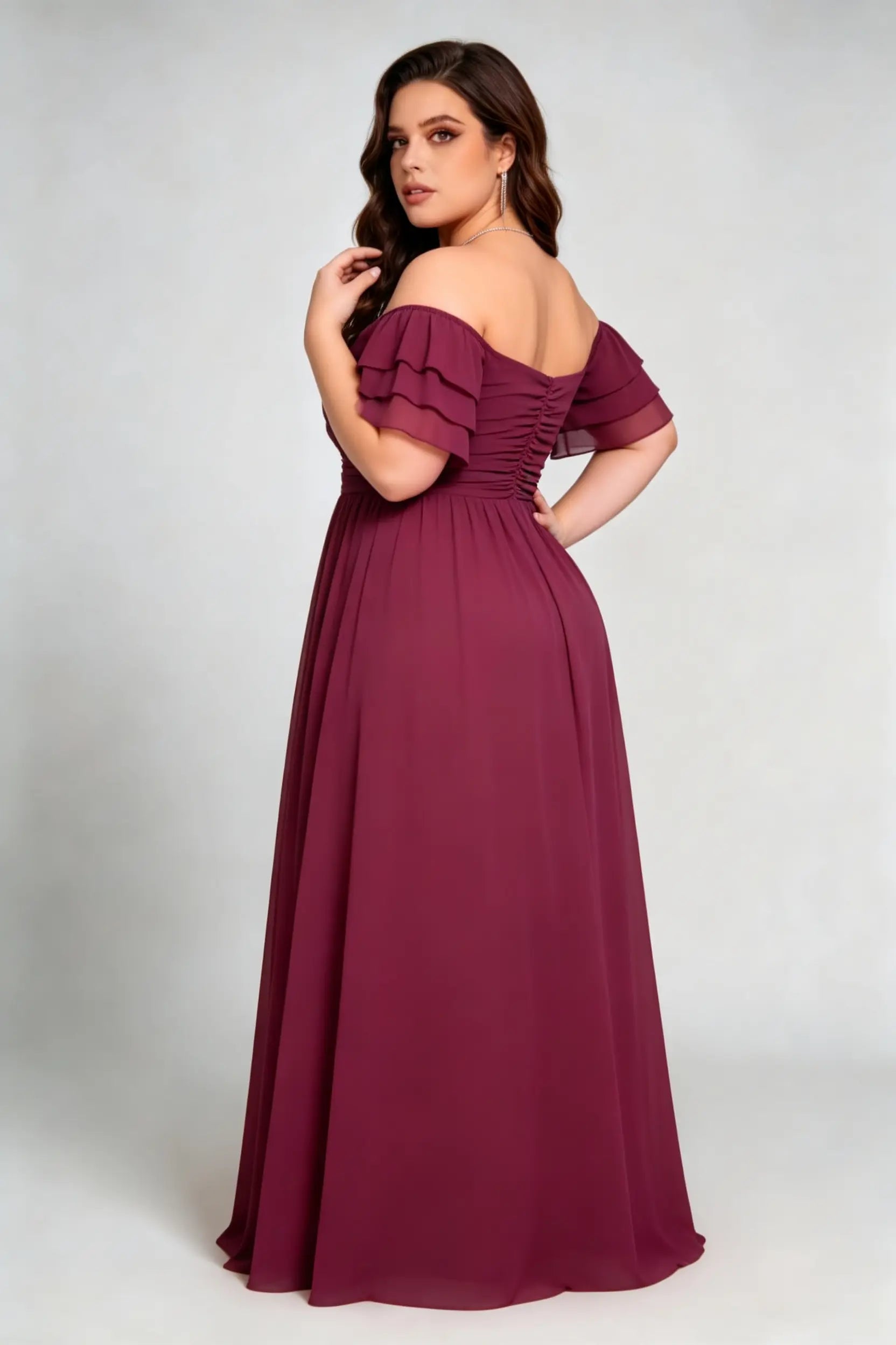 Curvy model wearing plus size burgundy off-the-shoulder tiered ruffle sleeve ruched back formal floor-length evening dress