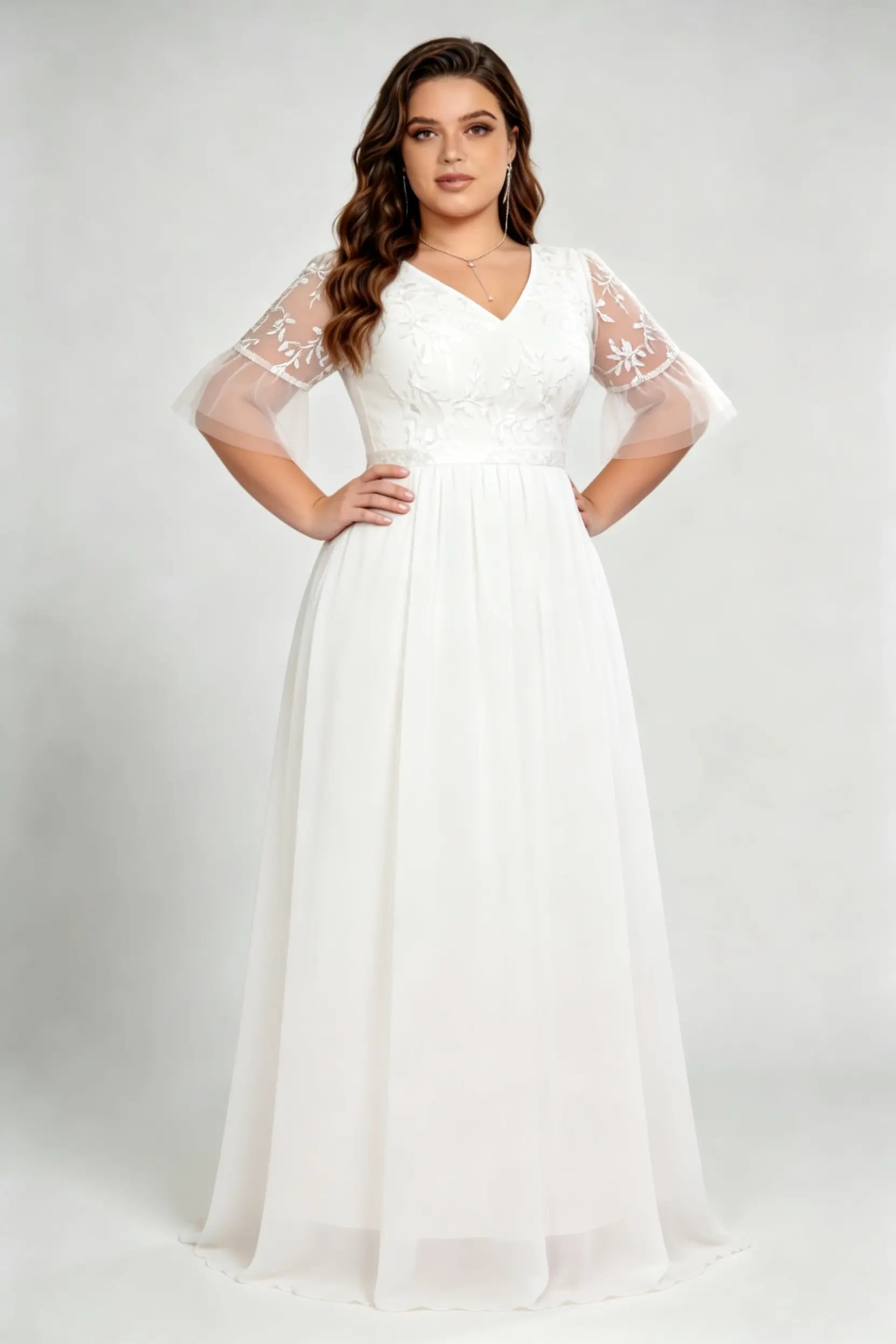 Curvy model wearing plus size white v-neck embroidered chiffon maxi wedding dress with flutter sleeves