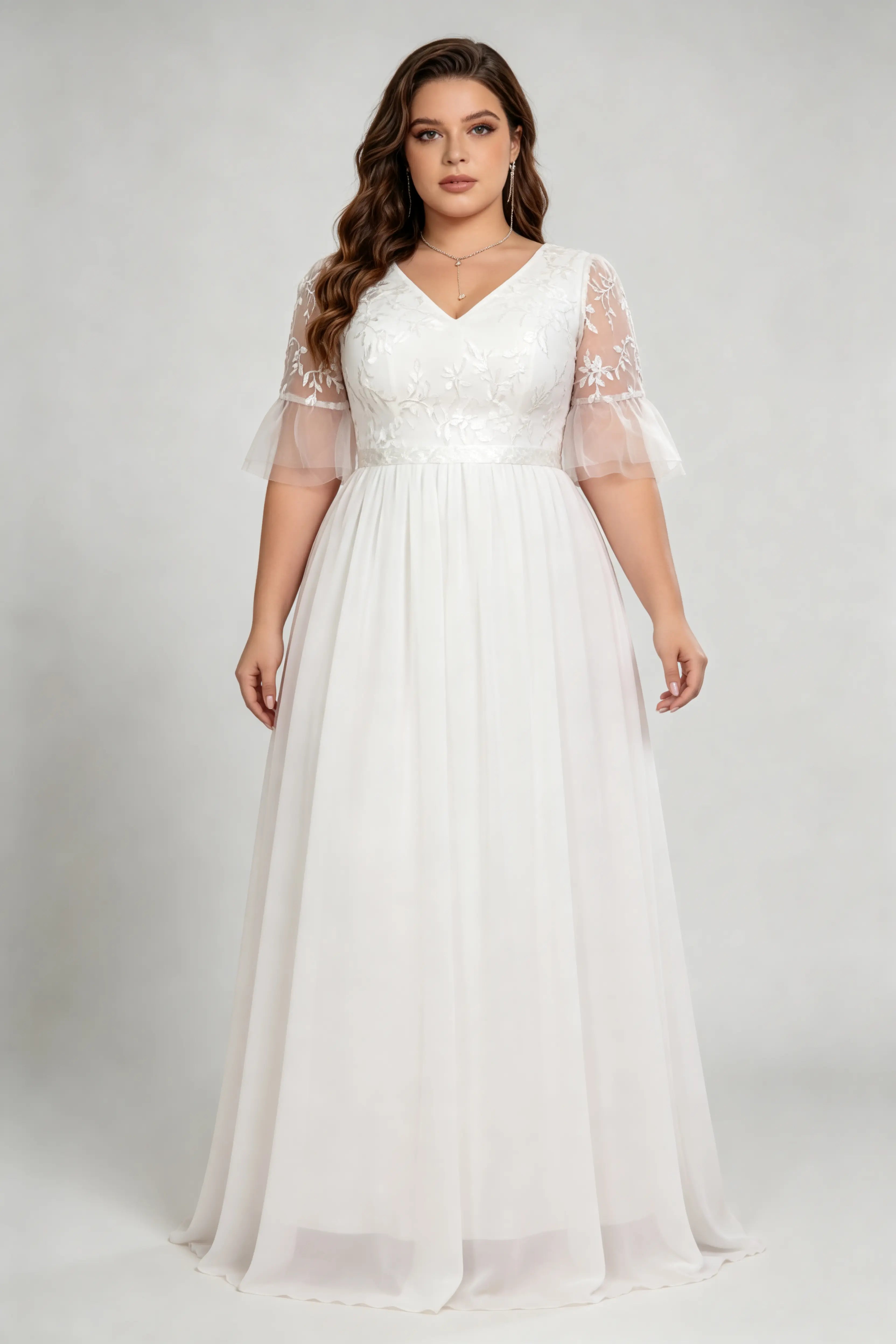 Curvy model wearing plus size white v-neck embroidered chiffon maxi wedding dress with flutter sleeves