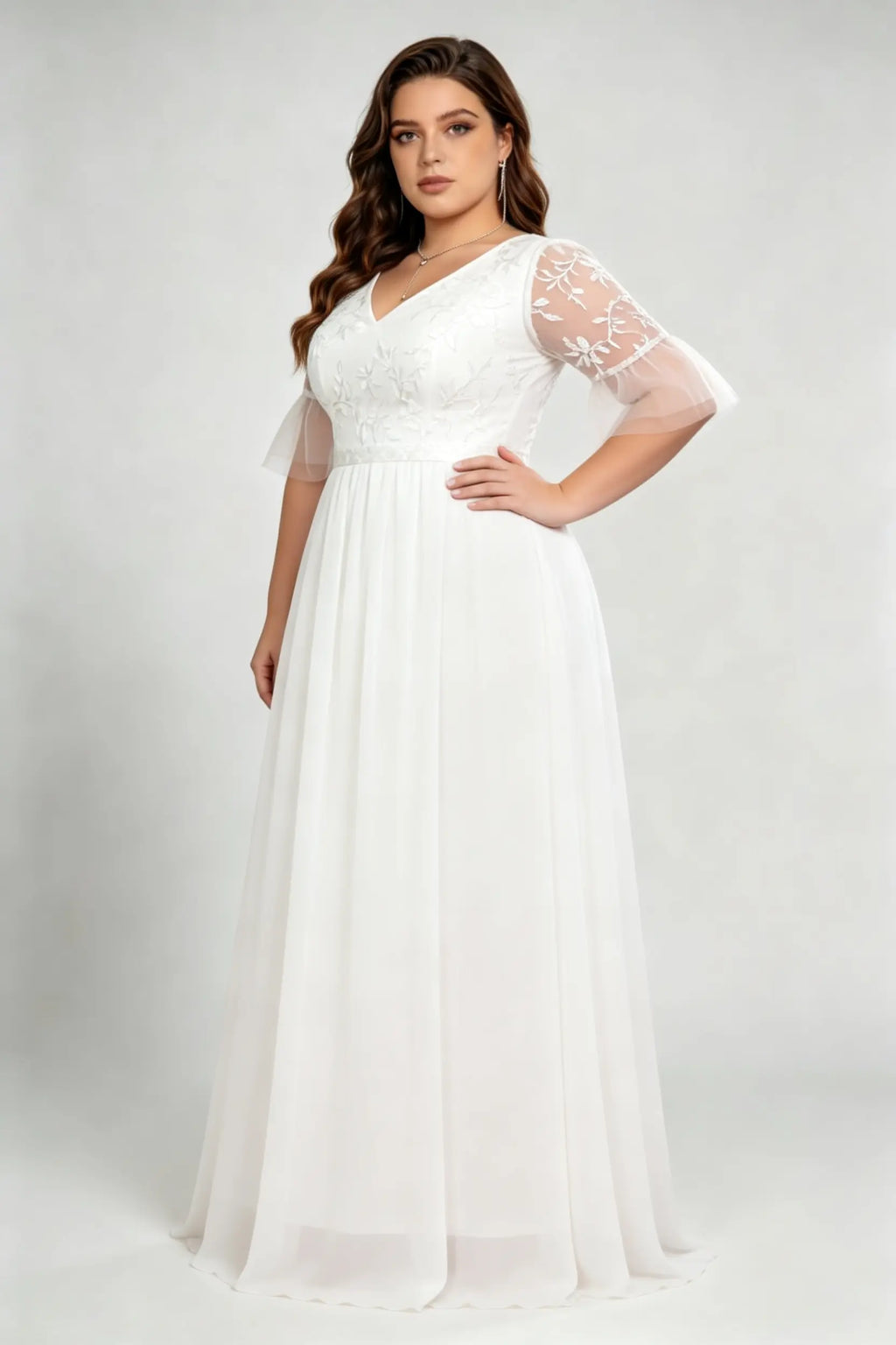 Curvy model wearing plus size white v-neck embroidered chiffon maxi wedding dress with flutter sleeves