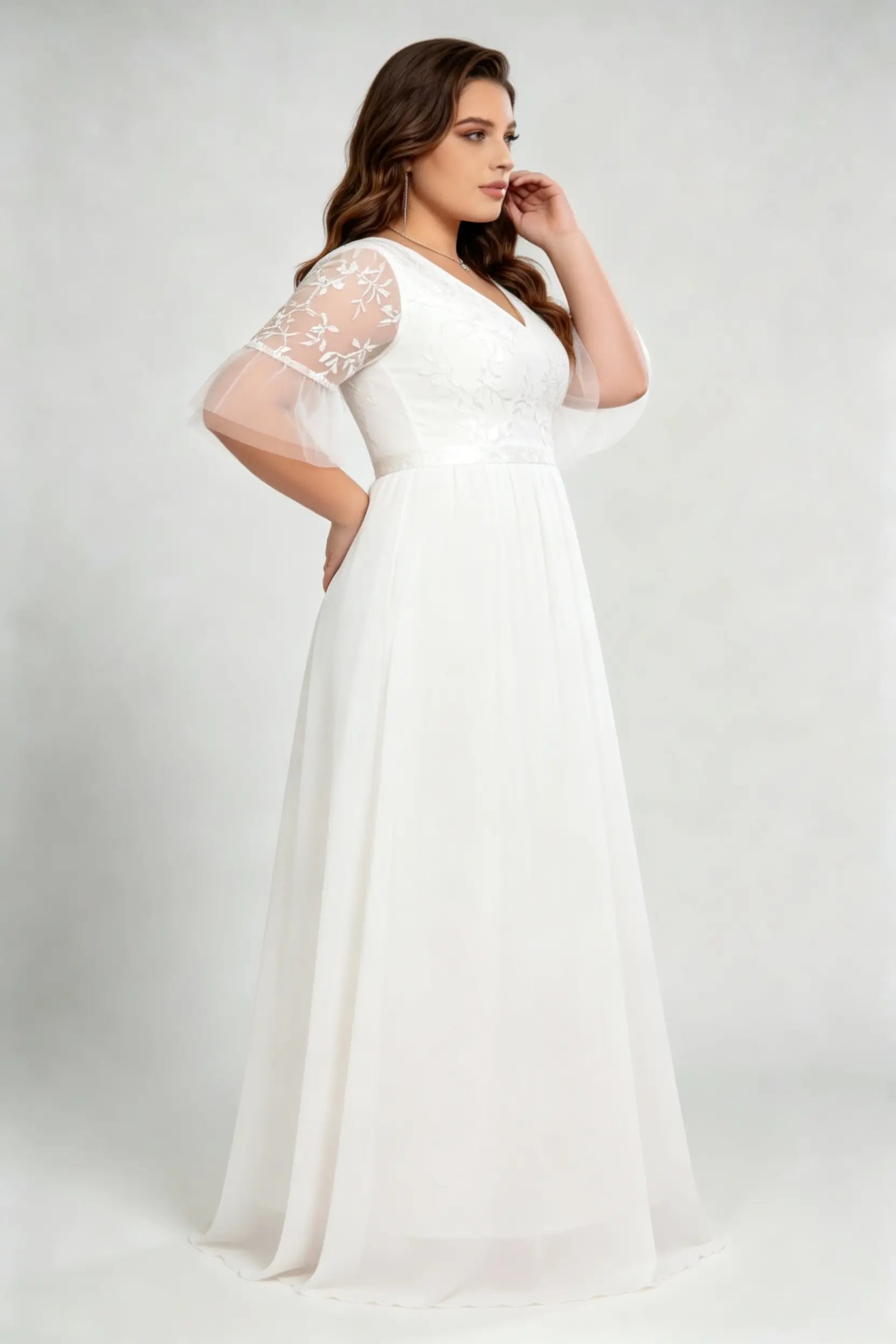 Curvy model wearing plus size white v-neck embroidered chiffon maxi wedding dress with flutter sleeves