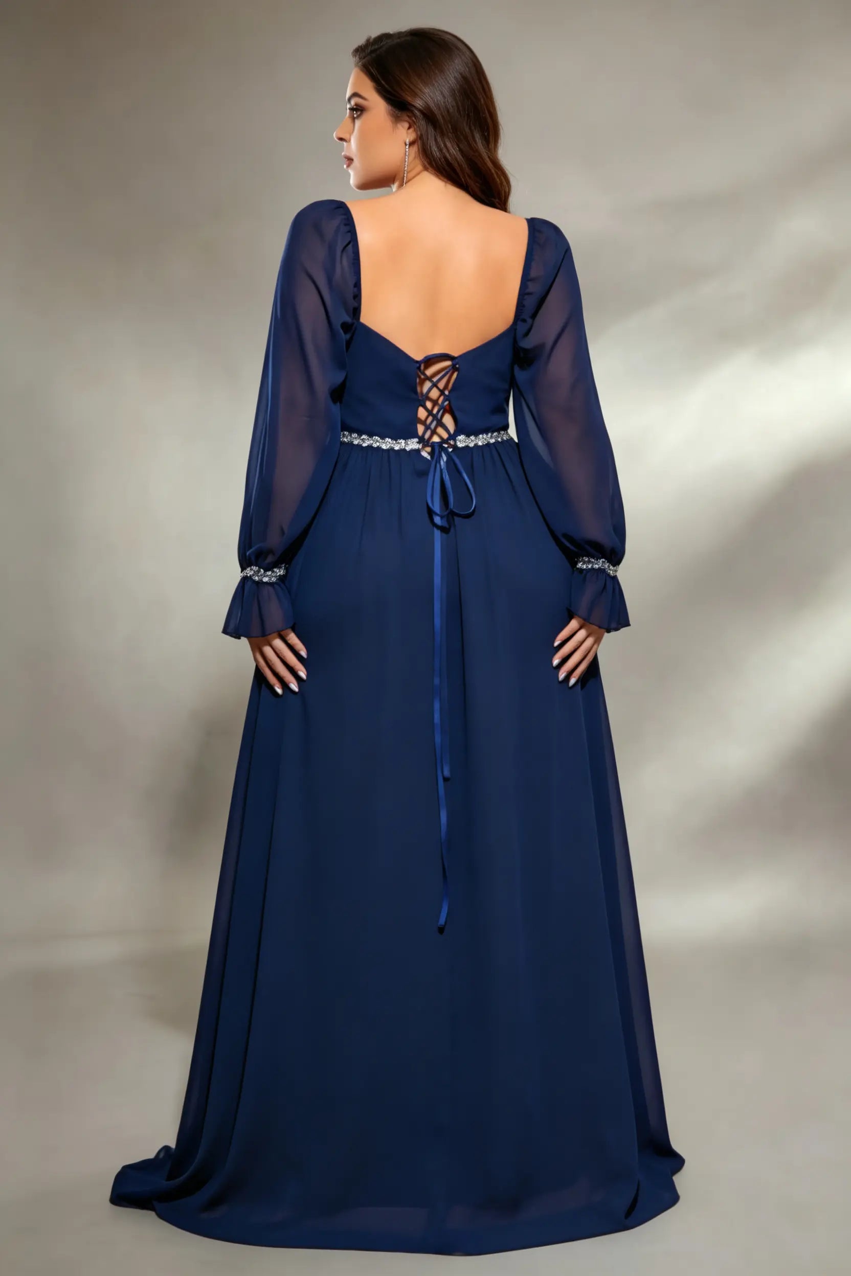 Curvy model wearing plus size navy square neck chiffon maxi evening gown with beaded trim and lace-up back