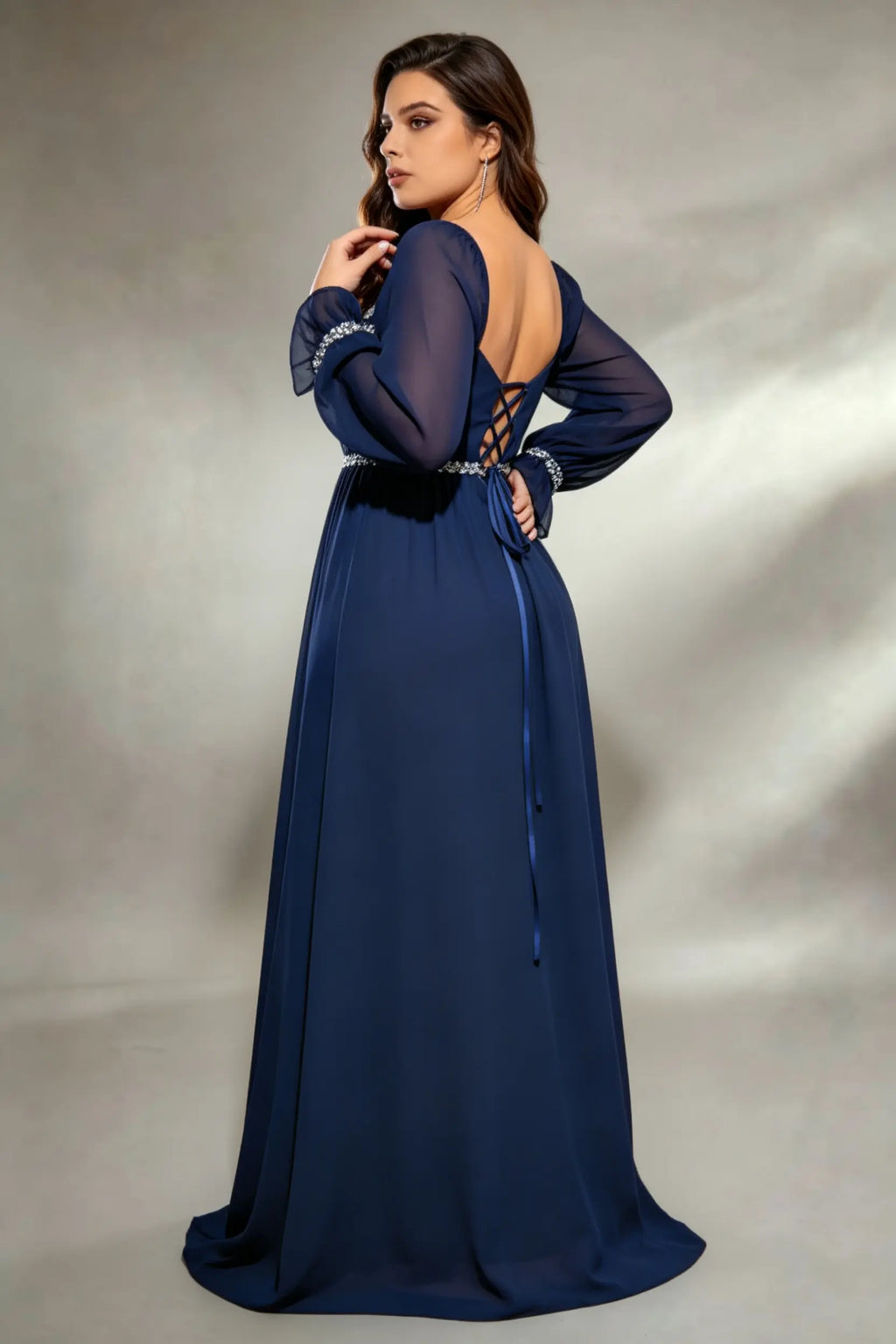 Curvy model wearing plus size navy square neck chiffon maxi evening gown with beaded trim and lace-up back