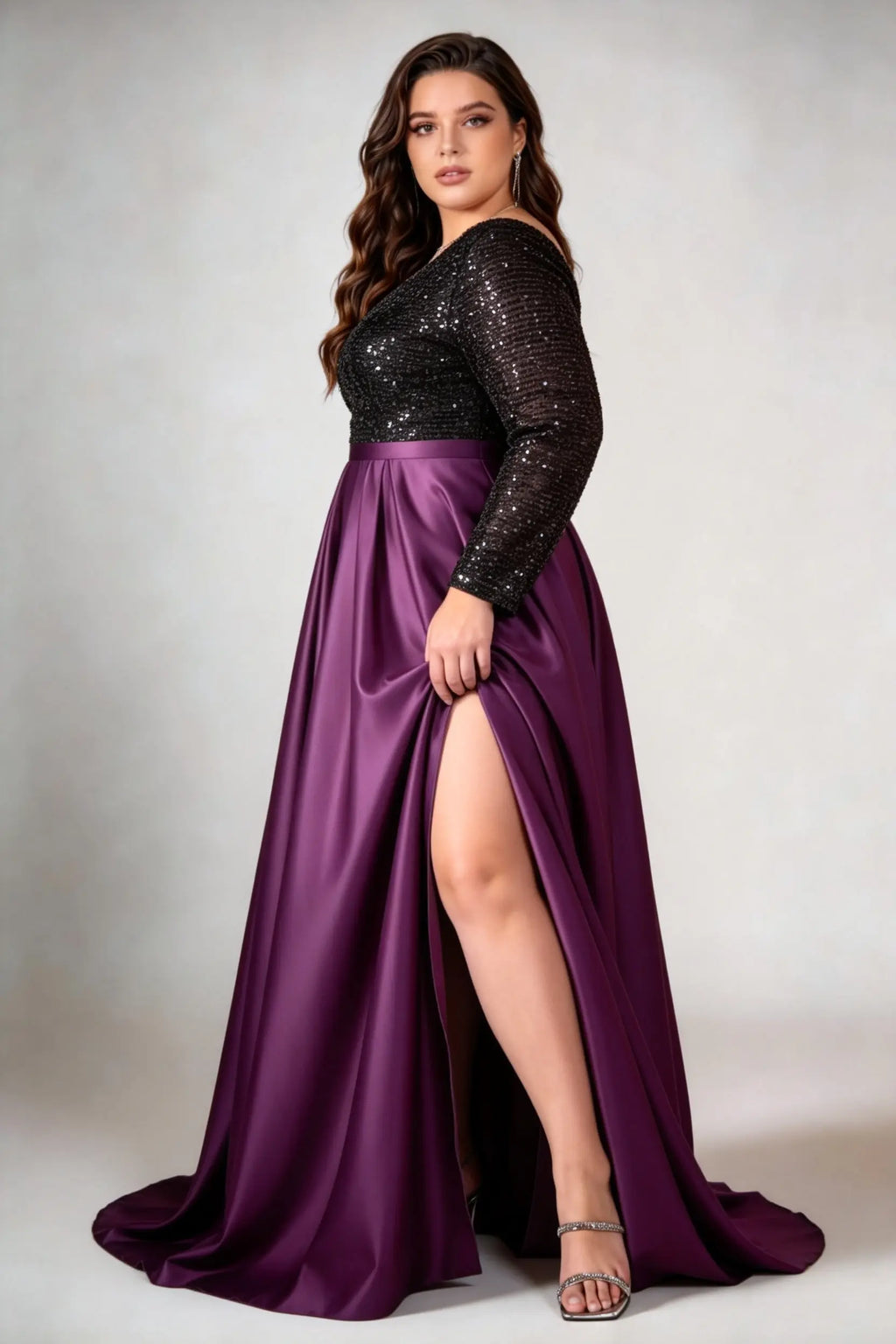 Curvy model wearing plus size black sequin v-neck long sleeve evening gown with high-slit satin skirt