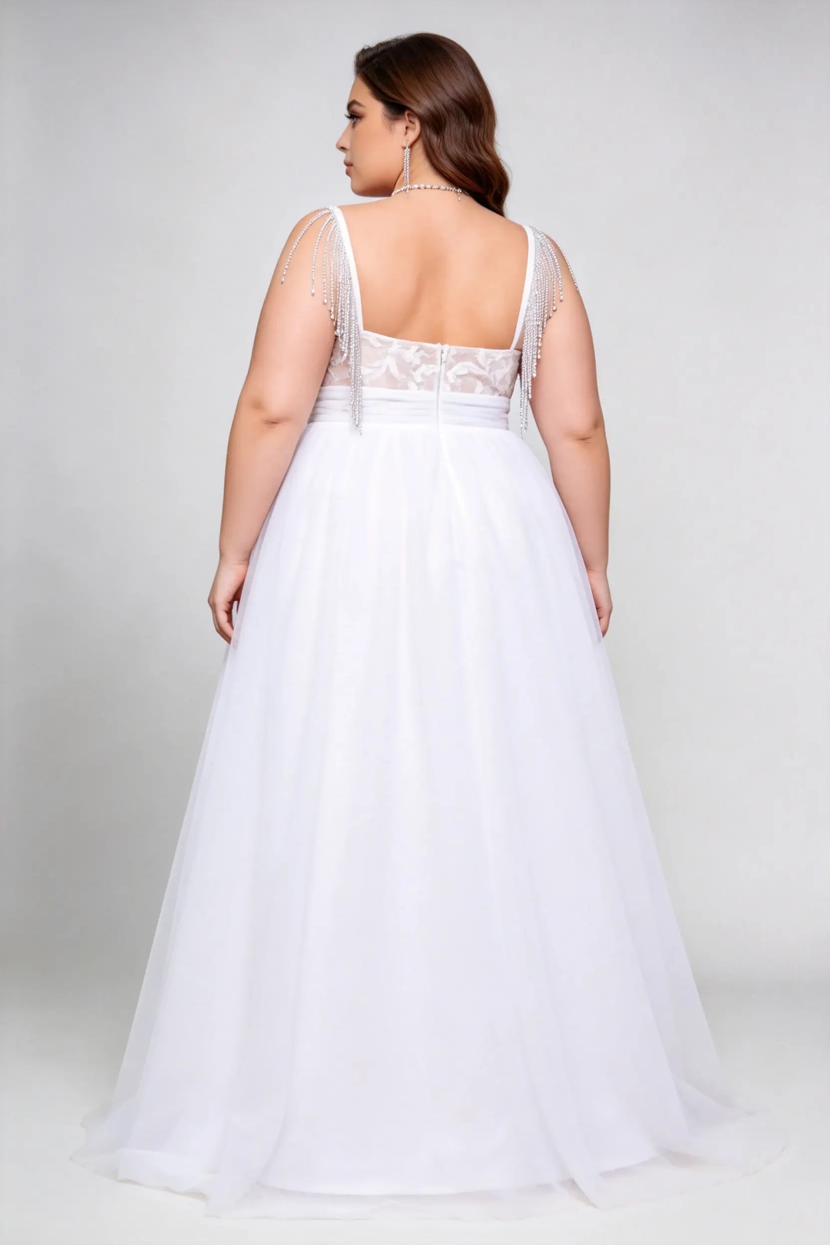 Curvy model wearing plus size white v-neck tulle bridal gown with rhinestone fringe shoulder straps