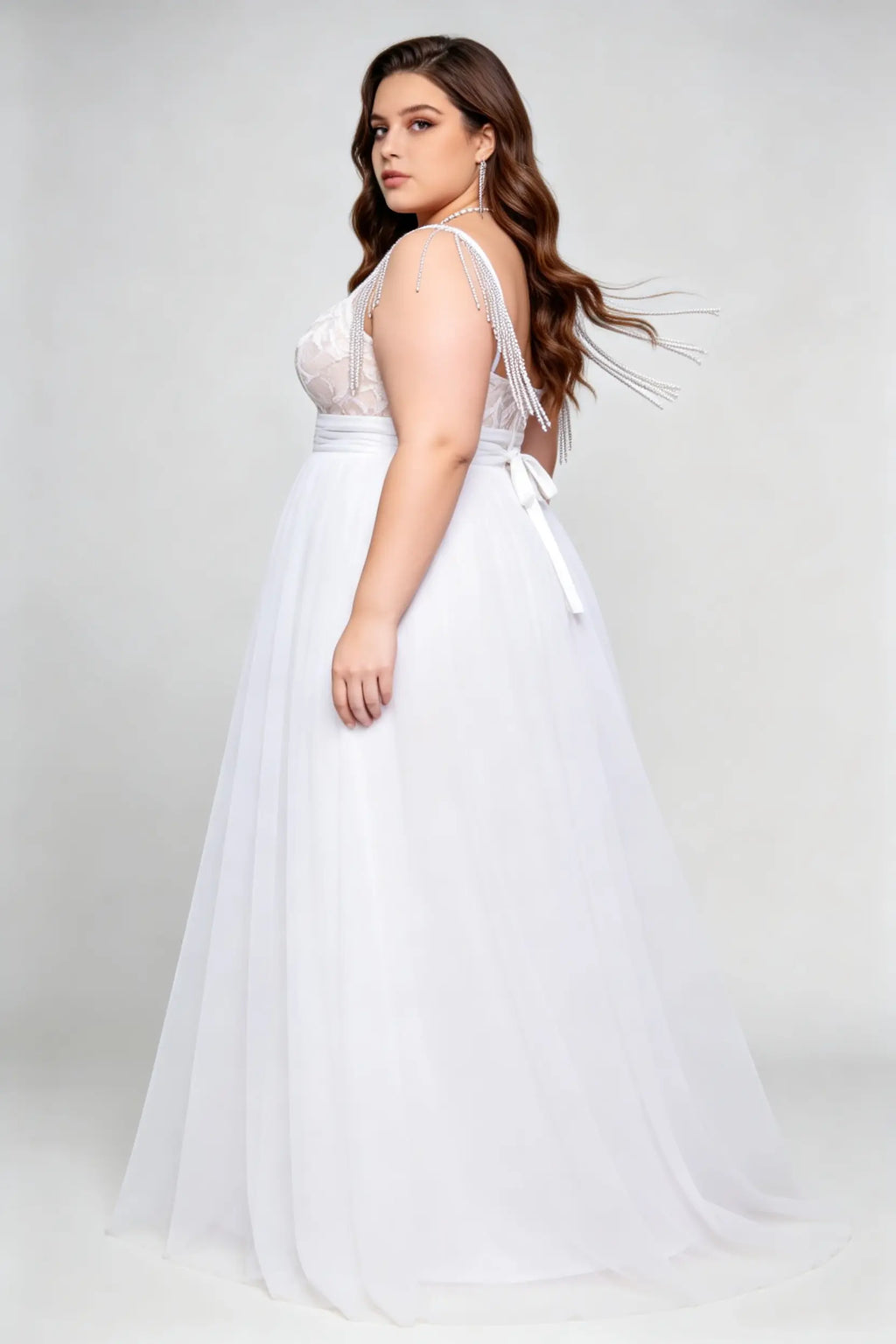 Curvy model wearing plus size white v-neck tulle bridal gown with rhinestone fringe shoulder straps