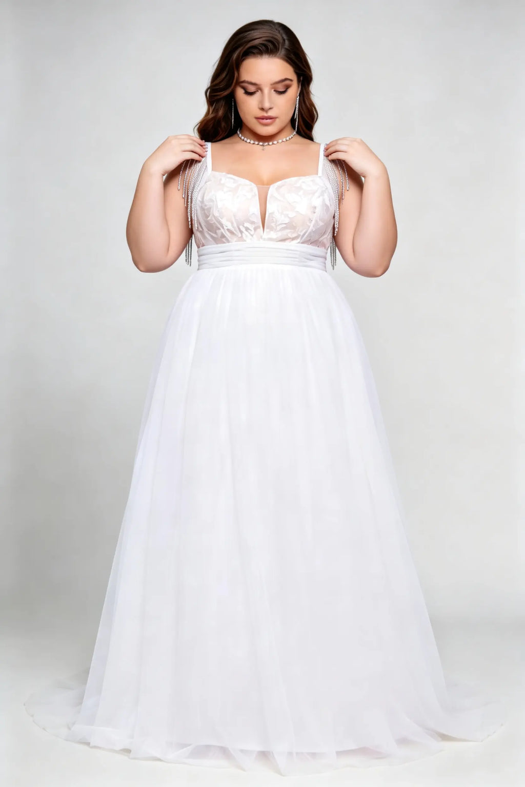 Curvy model wearing plus size white v-neck tulle bridal gown with rhinestone fringe shoulder straps