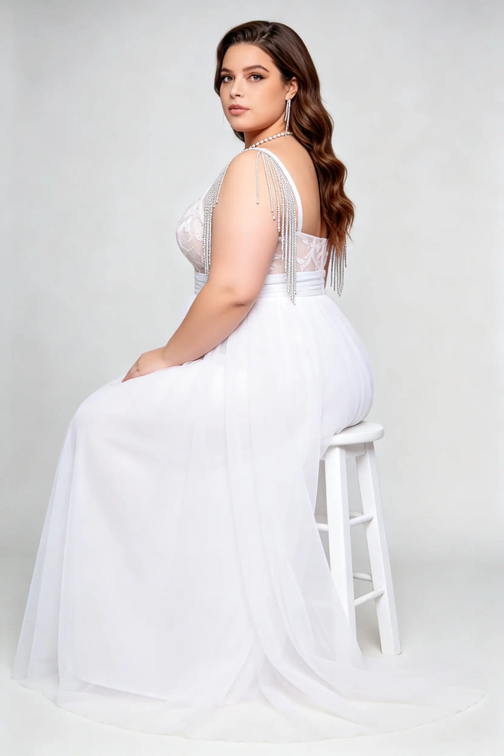 Curvy model wearing plus size white v-neck tulle bridal gown with rhinestone fringe shoulder straps
