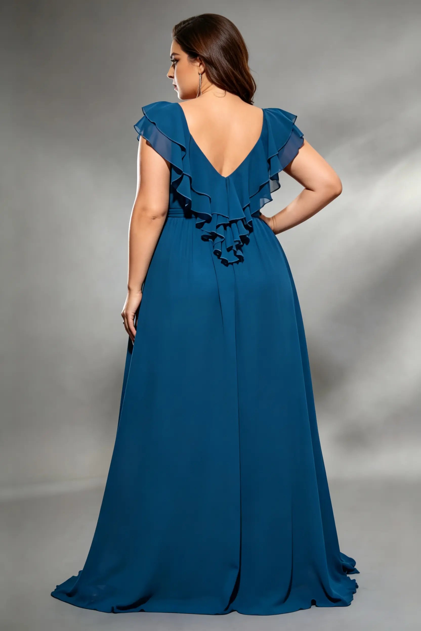 Curvy model wearing plus size navy v-neck teal blue chiffon maxi dress with cascading back ruffles