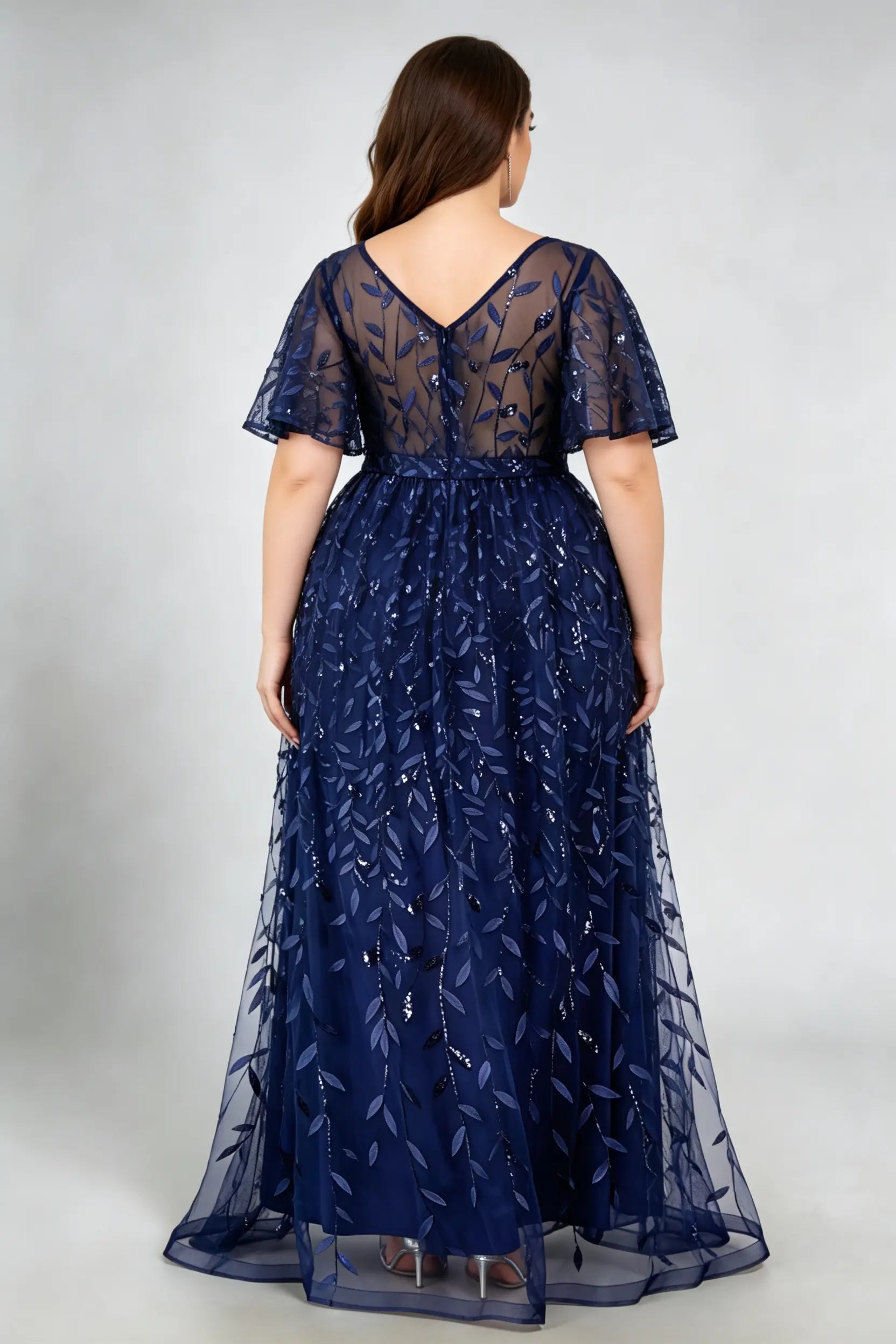 Curvy model wearing plus size navy sequined leaf flutter sleeve evening gown - elegant a-line prom & wedding guest maxi dress