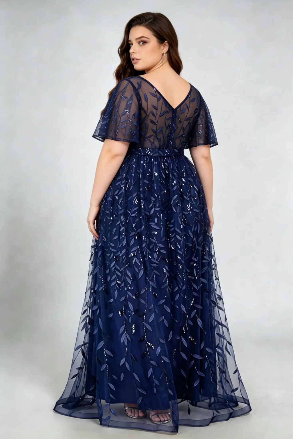 Curvy model wearing plus size navy sequined leaf flutter sleeve evening gown - elegant a-line prom & wedding guest maxi dress