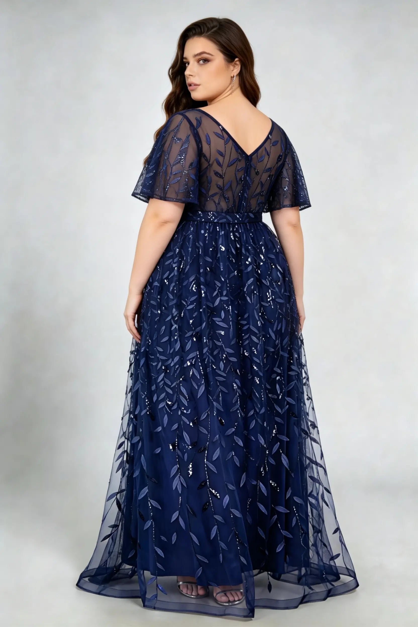 Curvy model wearing plus size navy sequined leaf flutter sleeve evening gown - elegant a-line prom & wedding guest maxi dress