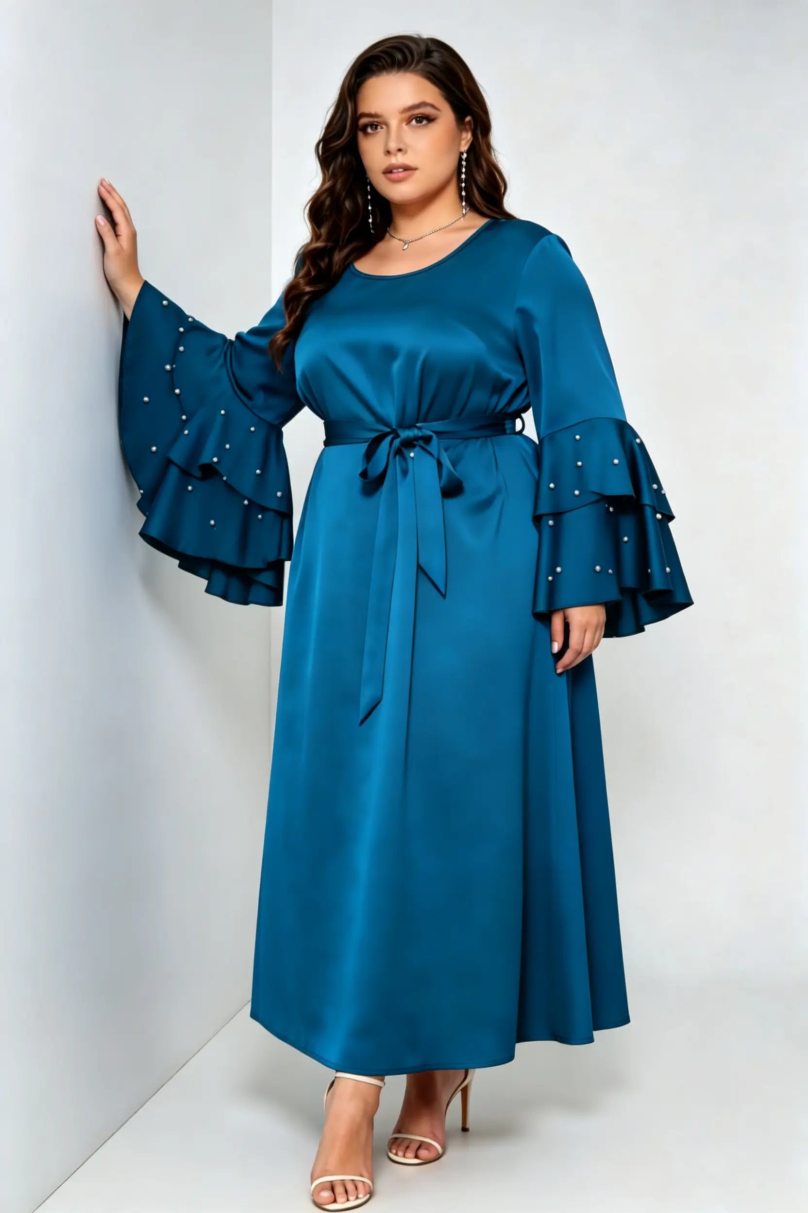 Curvy model wearing plus size teal blue satin maxi dress, tiered pearl flare sleeve round neck belted elegant evening dress