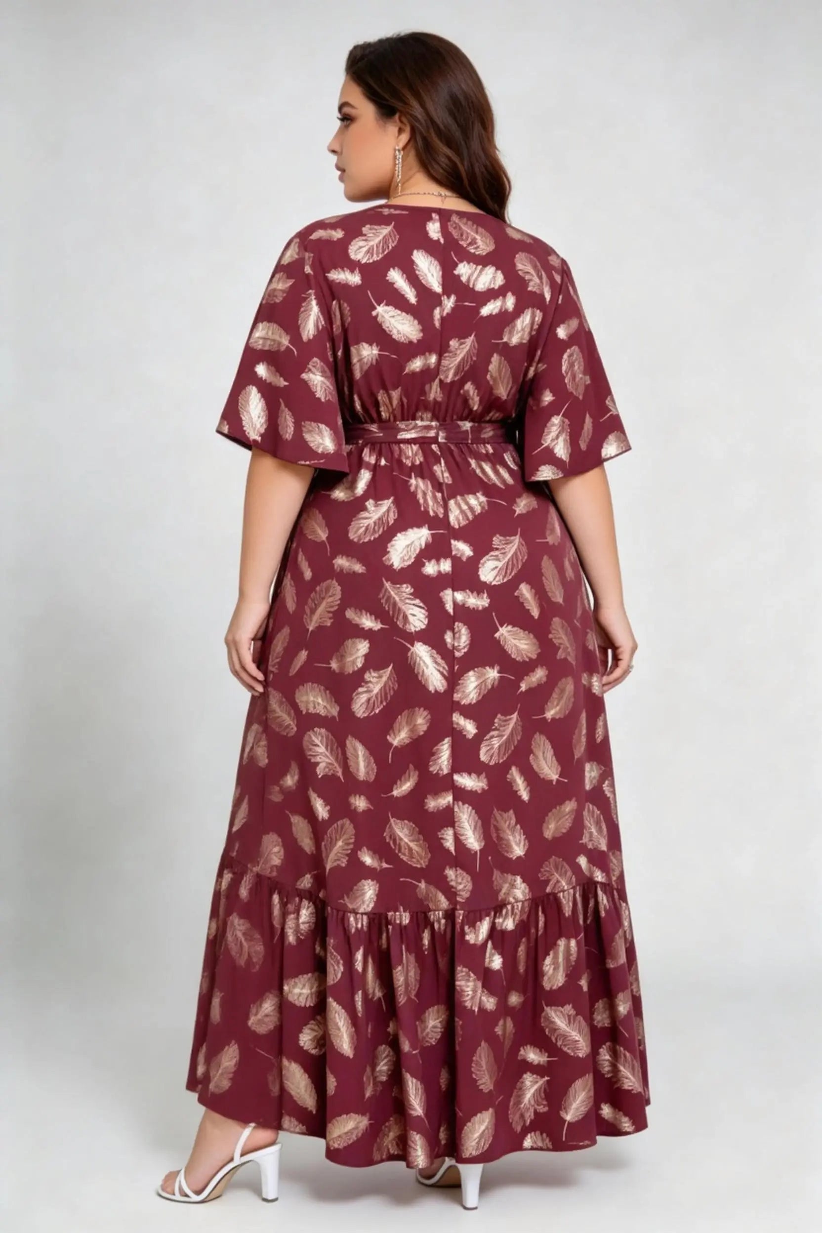 Curvy model wearing plus size wine red gold foil feather print maxi dress, v-neck flare sleeve high-low hem belted elegant summer dress