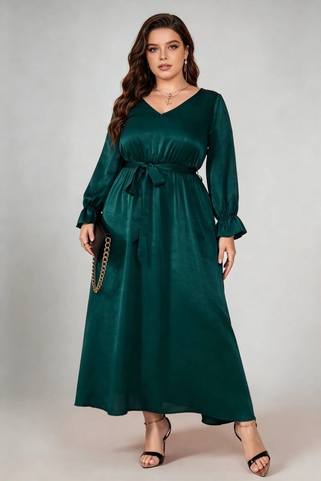 Curvy model wearing plus size dark green satin maxi dress, v-neck long sleeve ruffle cuff belted a-line elegant evening dress
