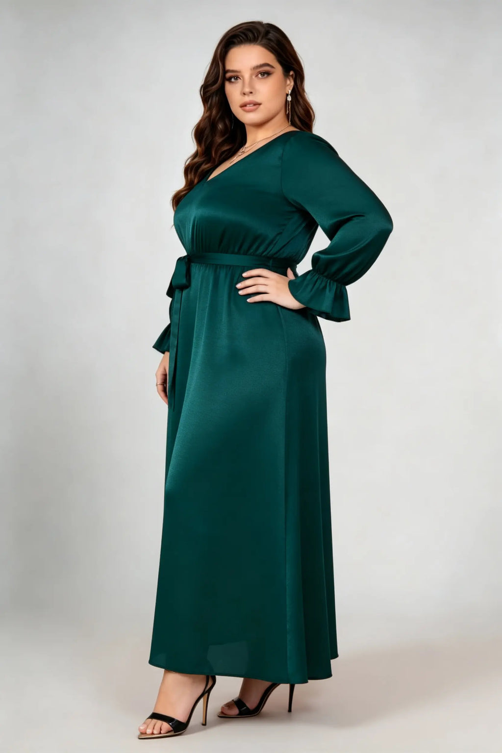 Curvy model wearing plus size dark green satin maxi dress, v-neck long sleeve ruffle cuff belted a-line elegant evening dress