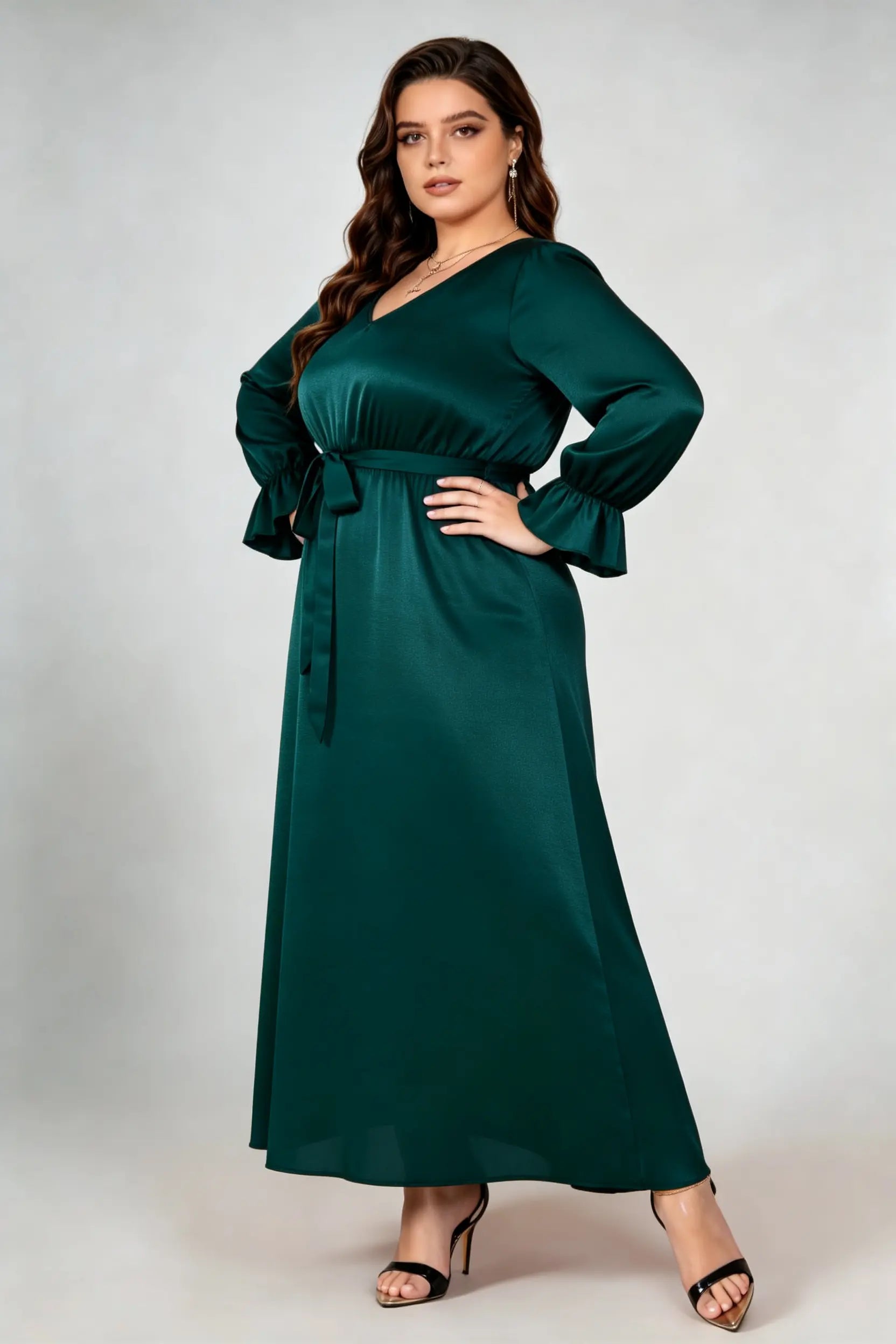 Curvy model wearing plus size dark green satin maxi dress, v-neck long sleeve ruffle cuff belted a-line elegant evening dress