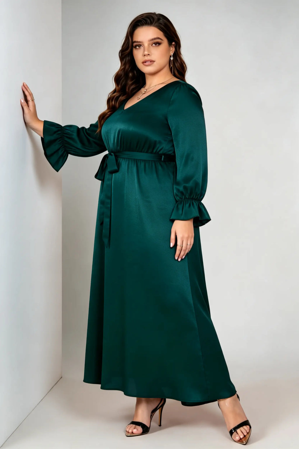 Curvy model wearing plus size dark green satin maxi dress, v-neck long sleeve ruffle cuff belted a-line elegant evening dress