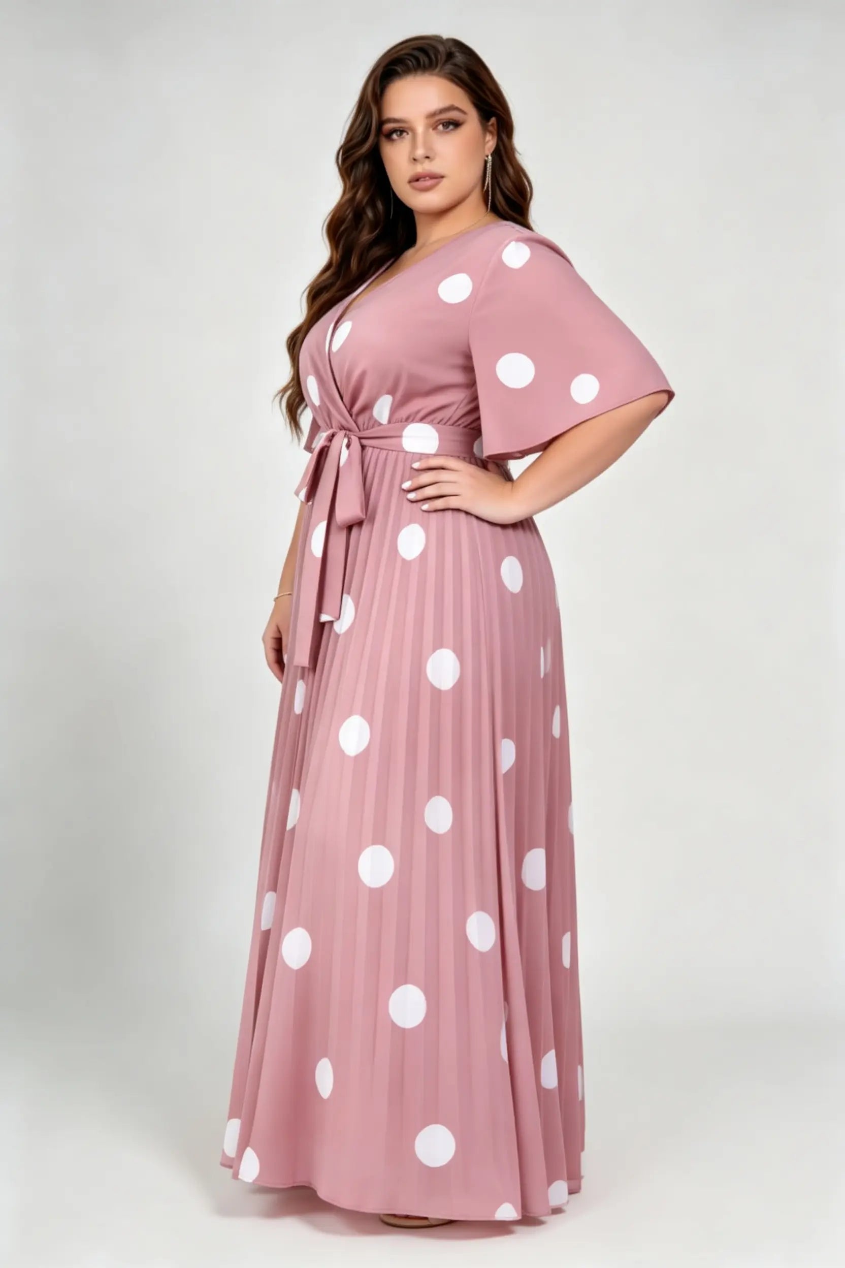 Curvy model wearing plus size pink polka dot pleated maxi dress, v-neck flutter sleeve belted chiffon a-line elegant summer dress