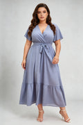 Curvy model wearing plus size blue polka dot wrap maxi dress, v-neck flutter sleeve a-line with belt, elegant summer dress