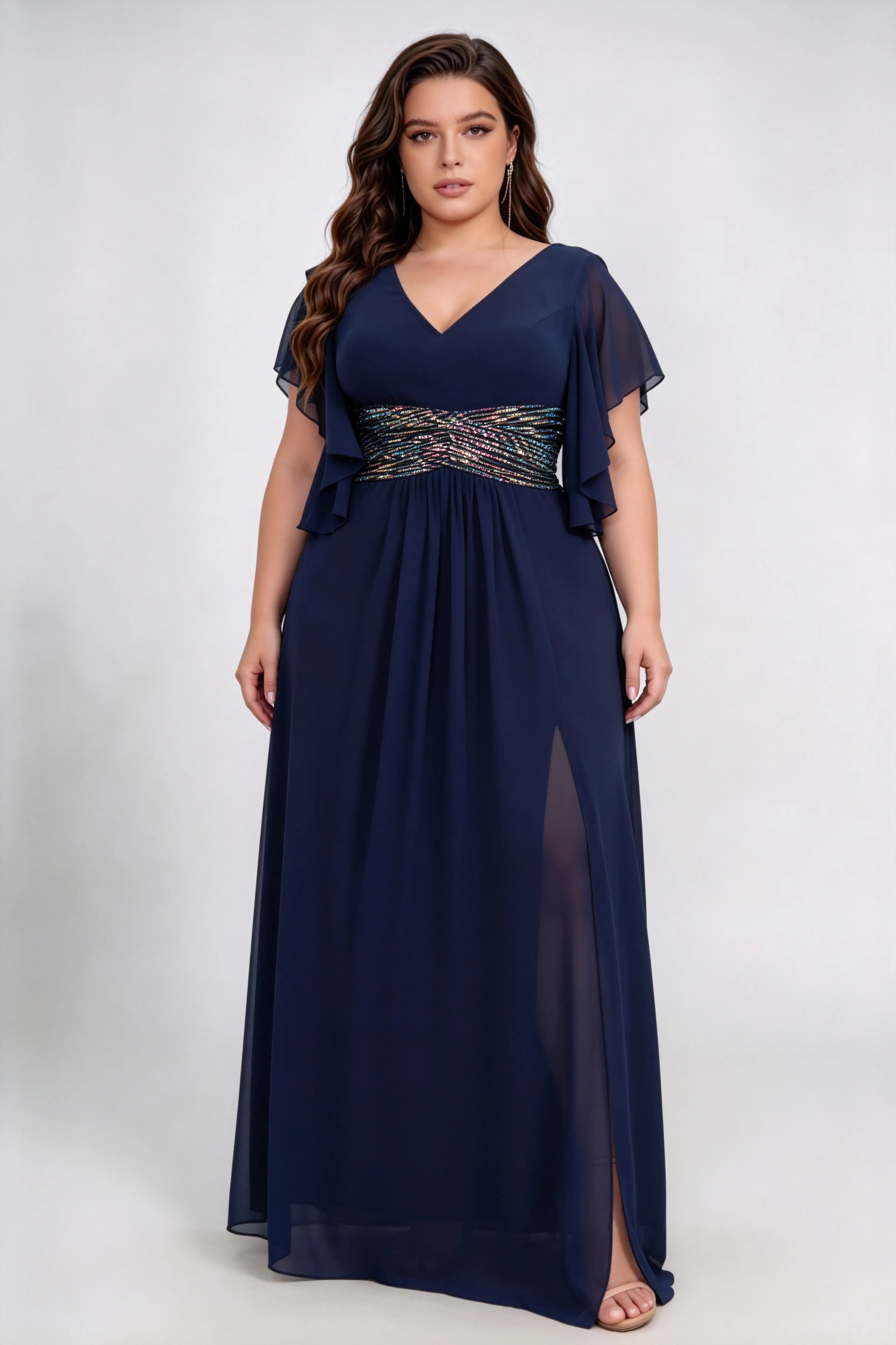 Curvy model wearing plus size navy v neck flutter sleeve ruched sequin waist chiffon high split maxi bridesmaid formal evening dress