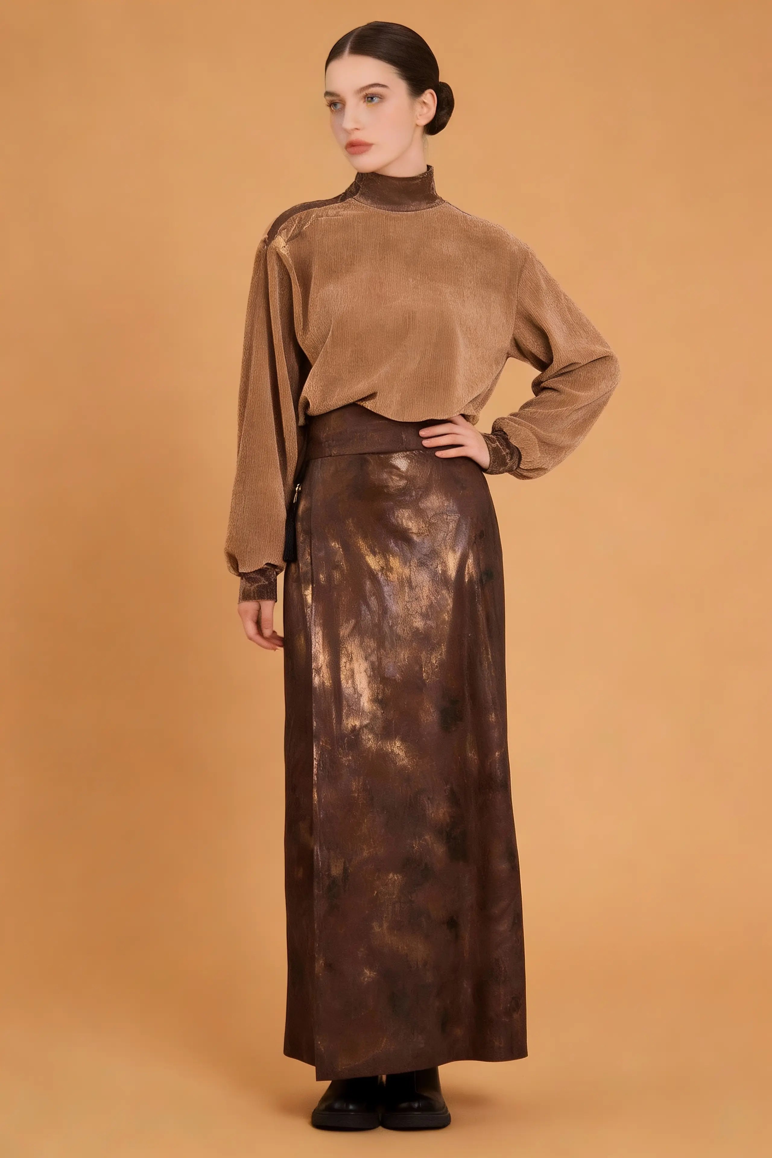 Woman wearing a brown velvet top and long skirt against a beige background