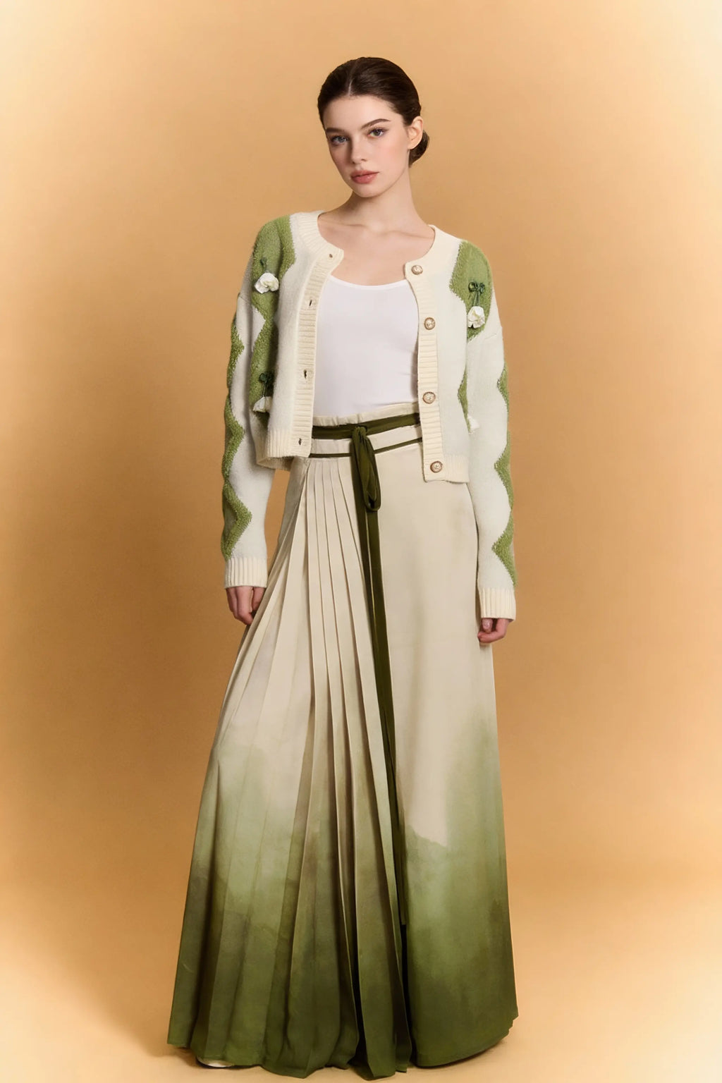 Woman wearing a Green & White Argyle Knit Cardigan with Pleated Ombre Skirt Set on a beige background