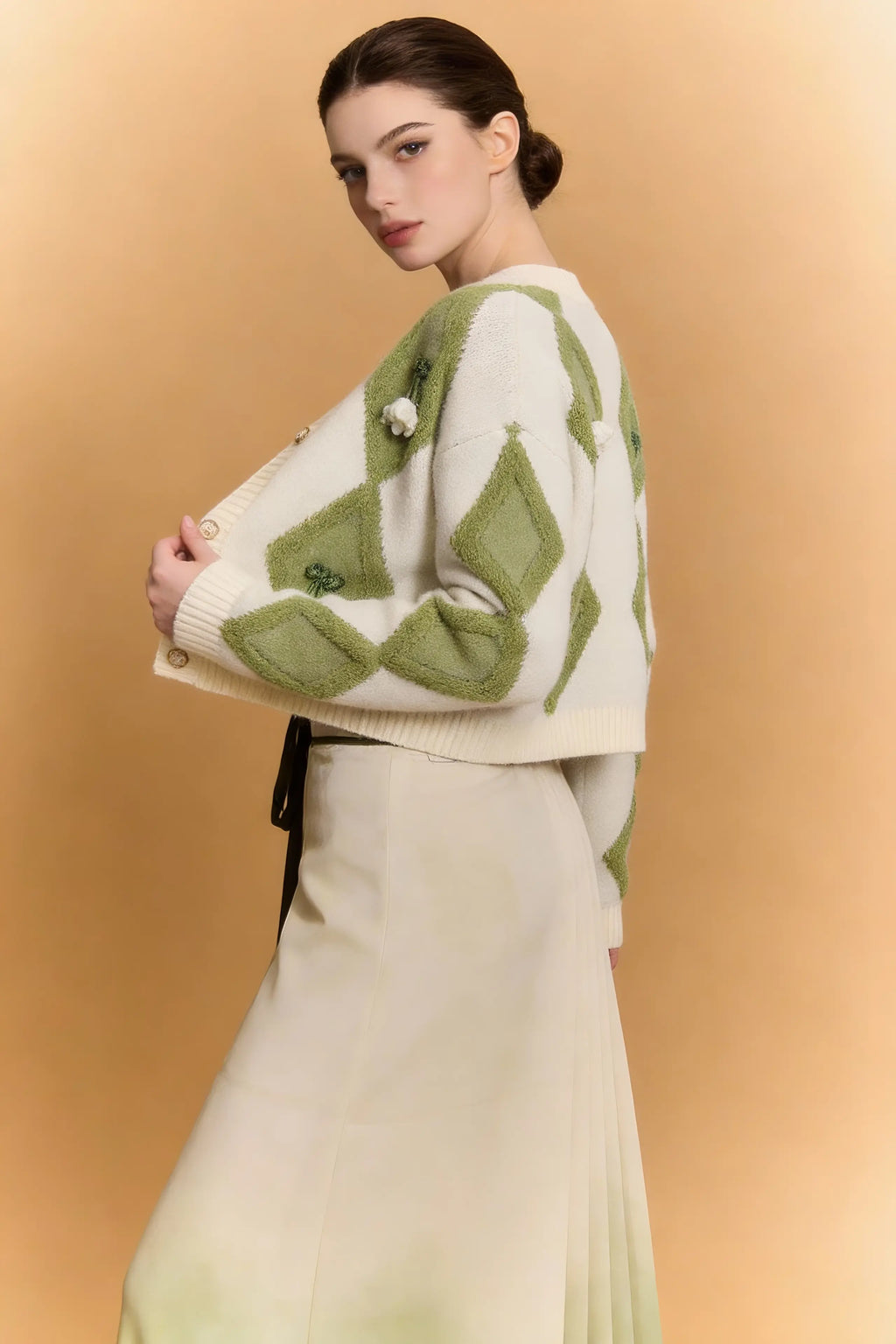 Woman wearing a Green & White Argyle Knit Cardigan with Pleated Ombre Skirt Set on a beige background