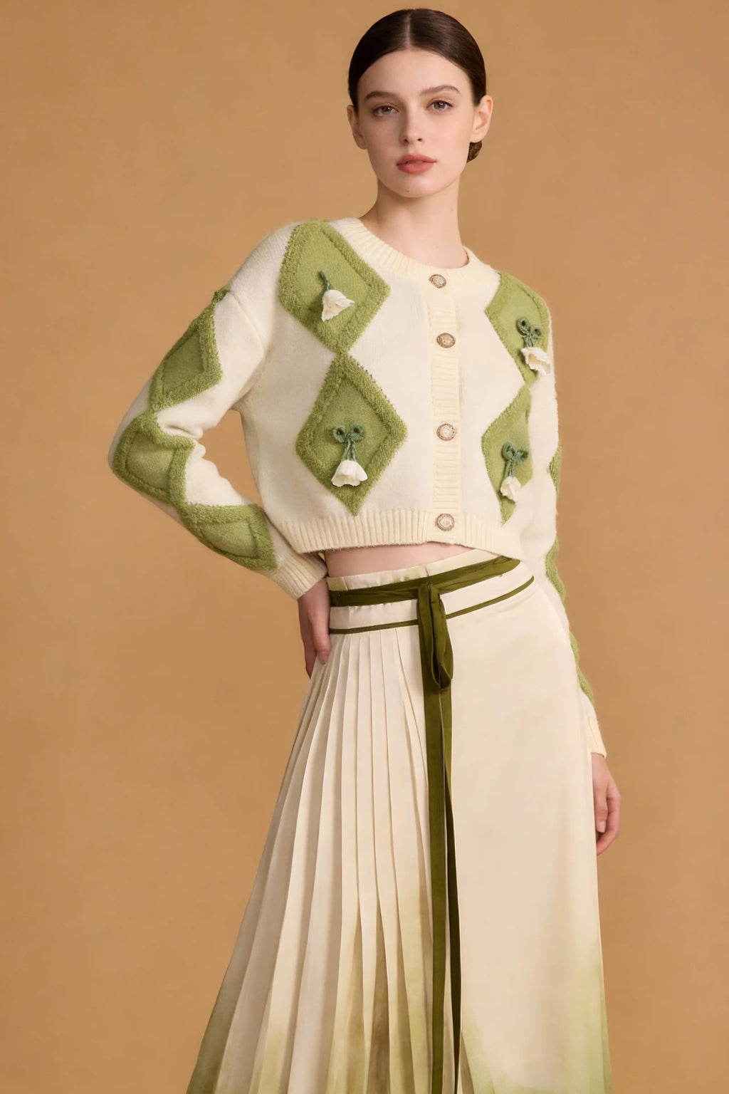 Woman wearing a Green & White Argyle Knit Cardigan with Pleated Ombre Skirt Set on a beige background