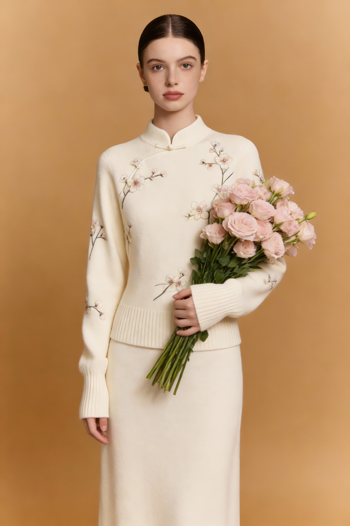 Woman in a cream-colored outfit holding pink flowers against a beige background