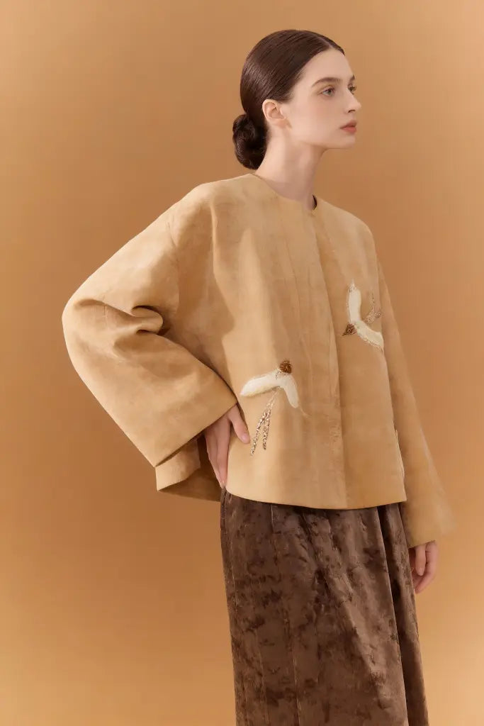 Woman wearing a Artisan Embroidered Linen Jacket with Bird Motifs - Beige Handcrafted Outerwear on a brown background