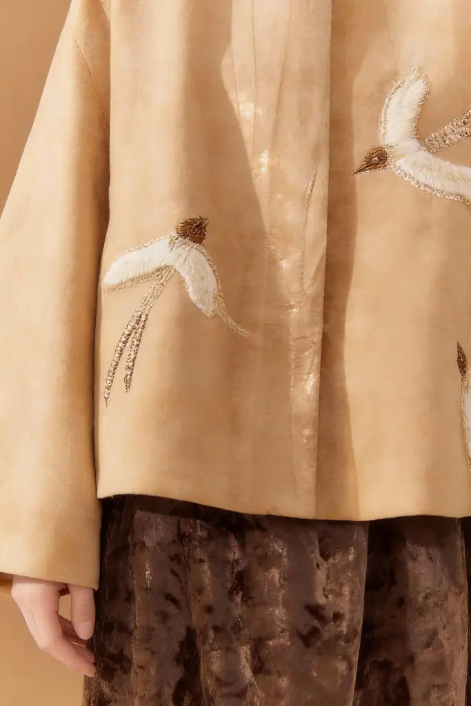 Woman wearing a Artisan Embroidered Linen Jacket with Bird Motifs - Beige Handcrafted Outerwear on a brown background