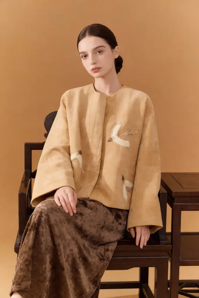Woman wearing a Artisan Embroidered Linen Jacket with Bird Motifs - Beige Handcrafted Outerwear on a brown background