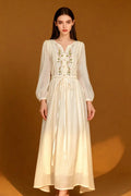 Woman wearing a Romantic Embroidered V-Neck Maxi Dress - White Boho Chic Long Sleeve Evening Gown on a brown background