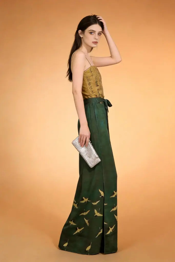 Woman wearing a green dress with bird patterns on an orange background