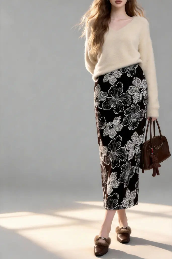 Woman wearing a floral black skirt and beige sweater on a gray background