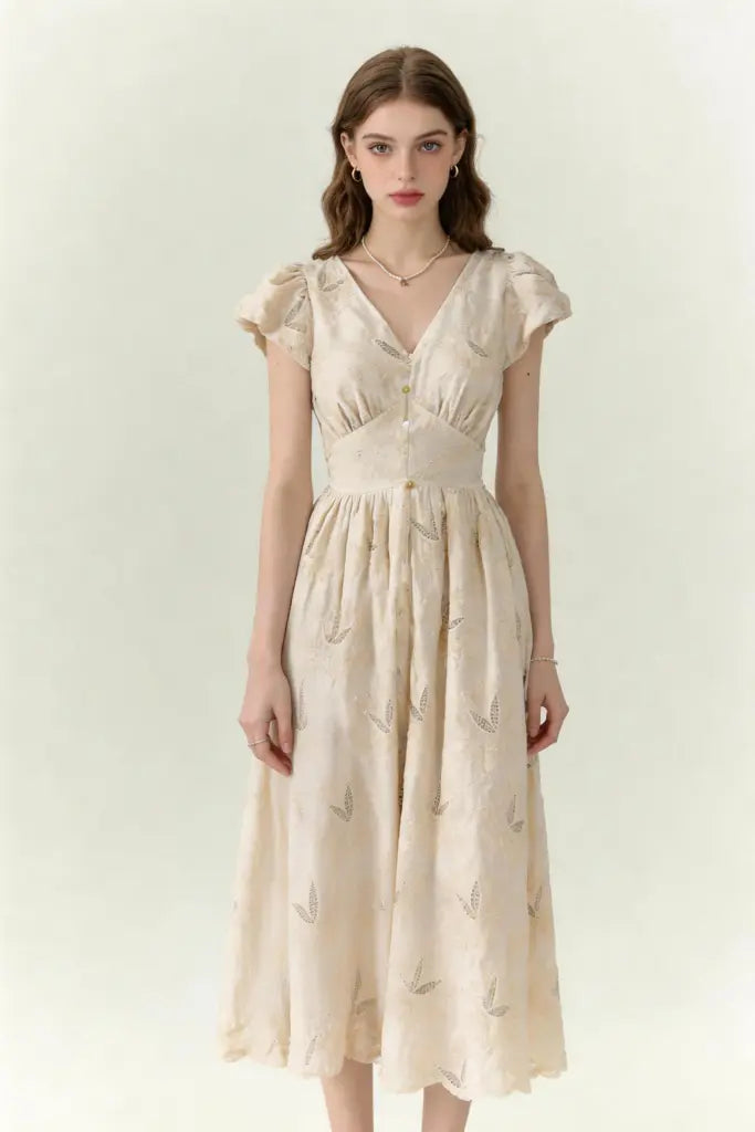 Woman wearing a beige dress with vintage embroidered linen-blend midi dress with ruffled cap sleeves on a white background
