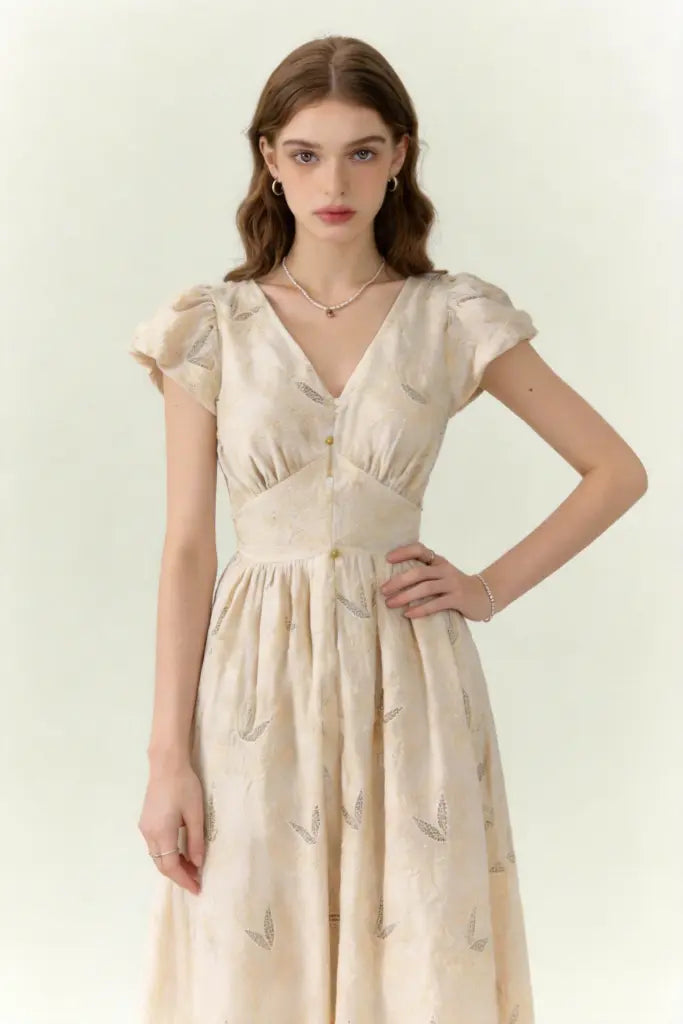 Woman wearing a beige dress with vintage embroidered linen-blend midi dress with ruffled cap sleeves on a white background