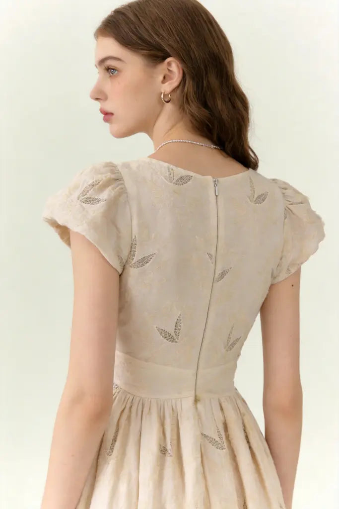 Woman wearing a beige dress with vintage embroidered linen-blend midi dress with ruffled cap sleeves on a white background
