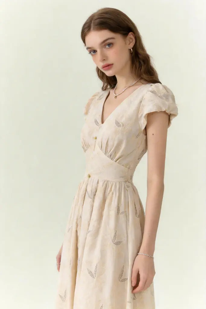 Woman wearing a beige dress with vintage embroidered linen-blend midi dress with ruffled cap sleeves on a white background