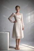 Women wearing a white elegant lace chiffon midi dress with square neck & puff sleeves against a gray background