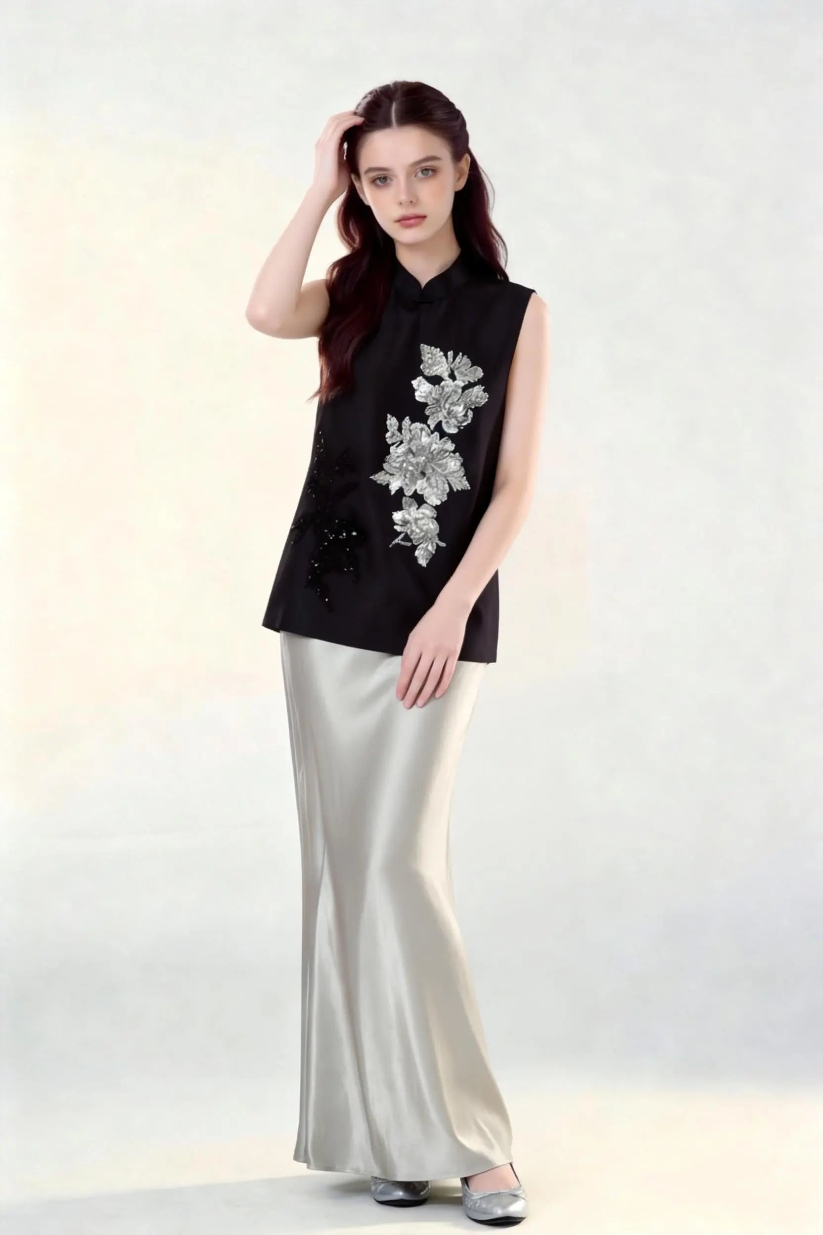 Woman wearing a black Beaded Lotus Embroidery Loose Sleeveless Top & Satin Skirt Two-Piece Set, holding a woven bag on a white background.