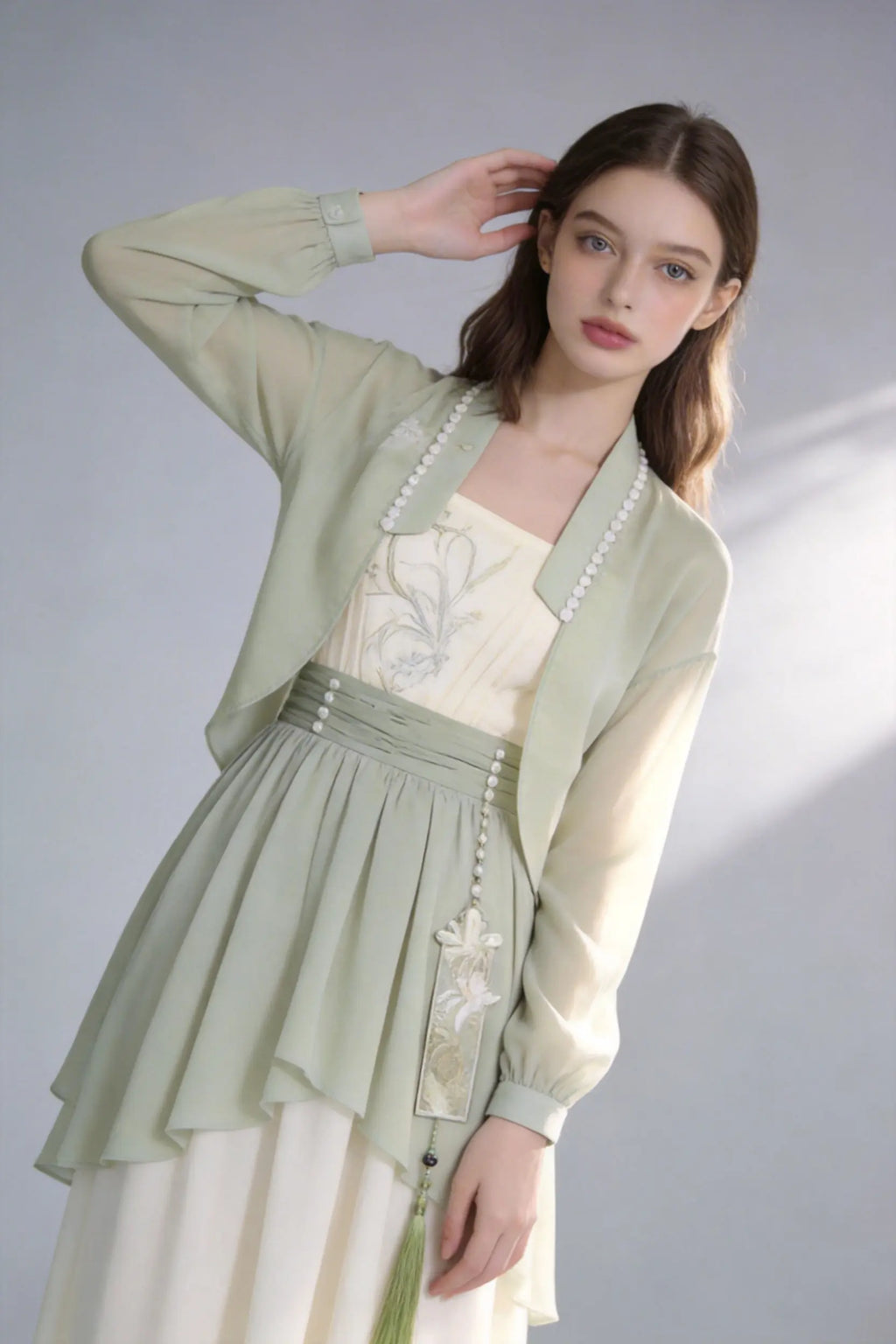 Woman wearing a Elegant Sage Green Chiffon Cardigan & Cream Dress Set - Modern Hanfu Inspired Two-Piece Outfit
 on a gray background